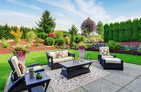 Backyard patio with furniture surrounded by greenery.