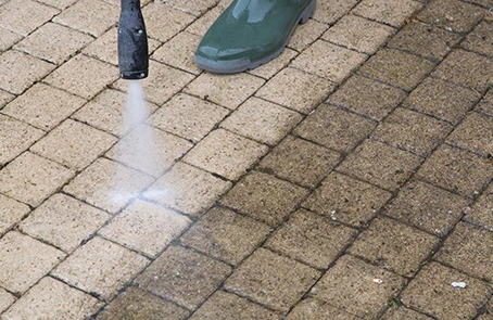 Person power washing pavers.