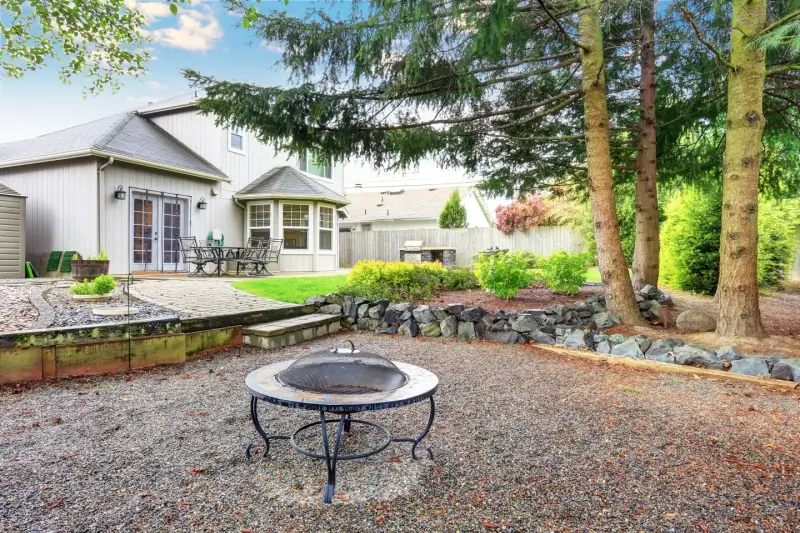 Fire pit in backyard with river rock landscaping.