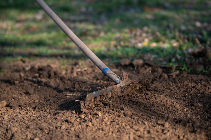 Landscaper tilling soil in garden